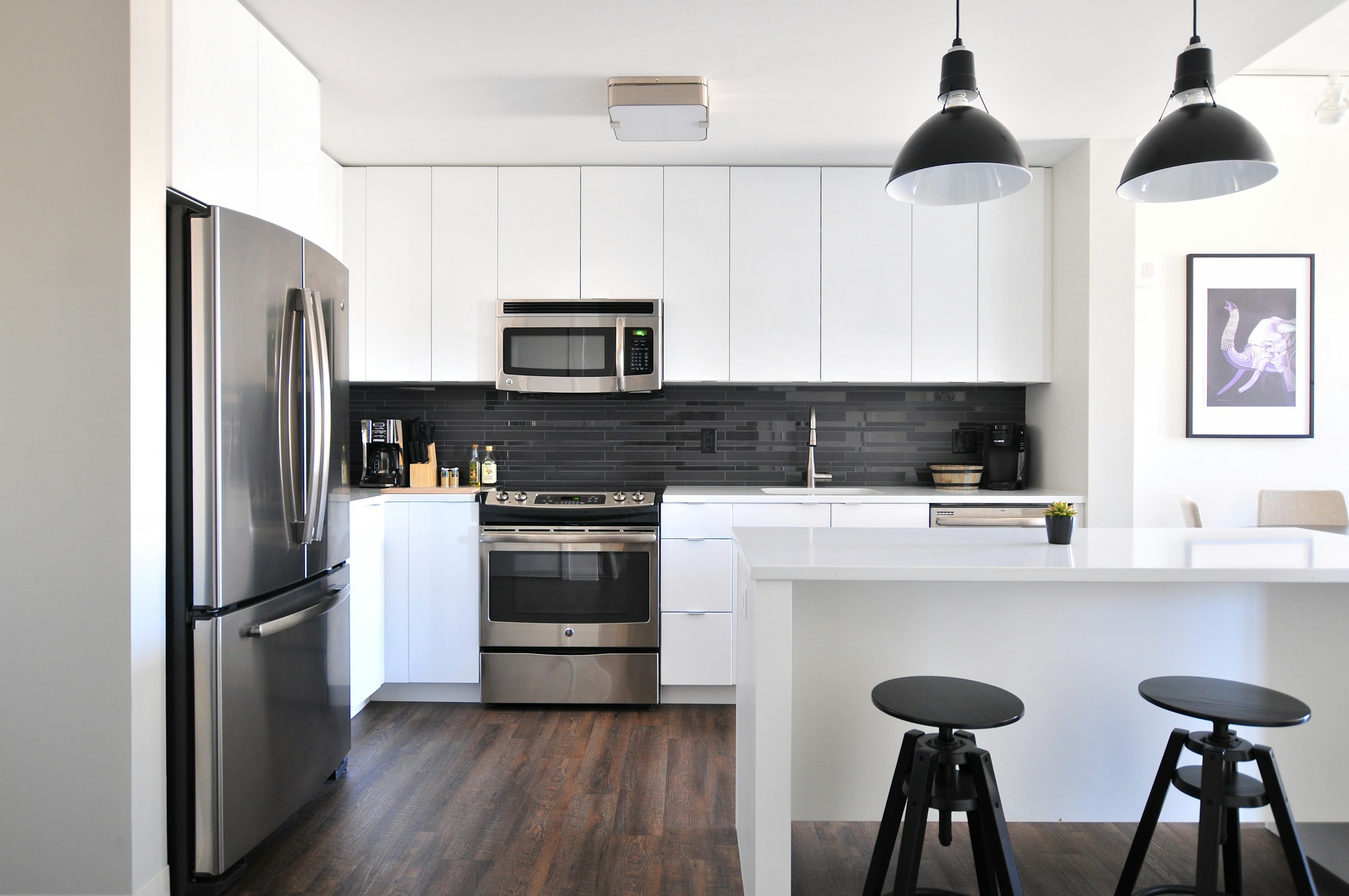 Modern white kitchen with black backsplash and pendant lights